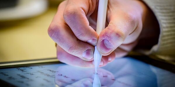 person holding stylus to write on tablet