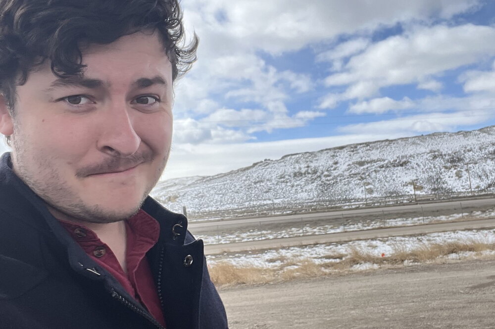 Richard Young posing in front of a prairie and mountain.