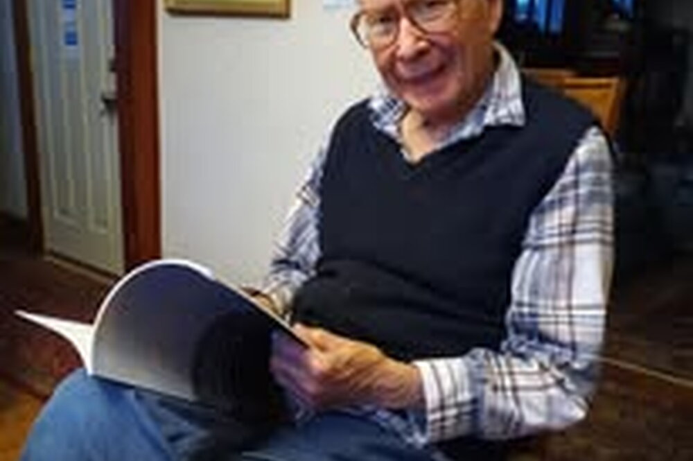 Robert McColley holding an open book in his home