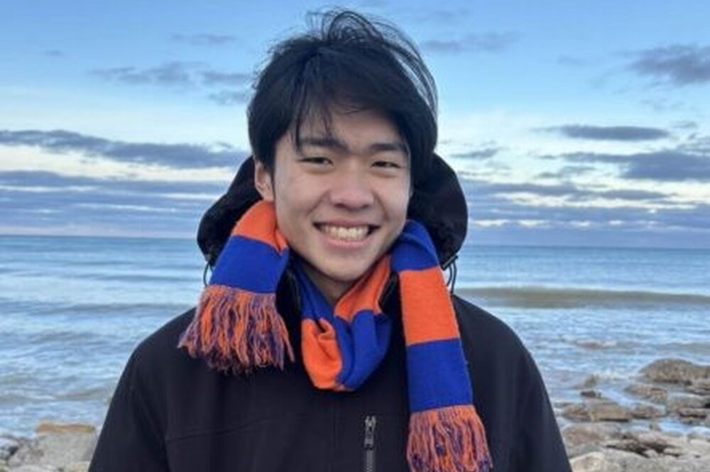 Lyndon Shi stands in front of a lake.