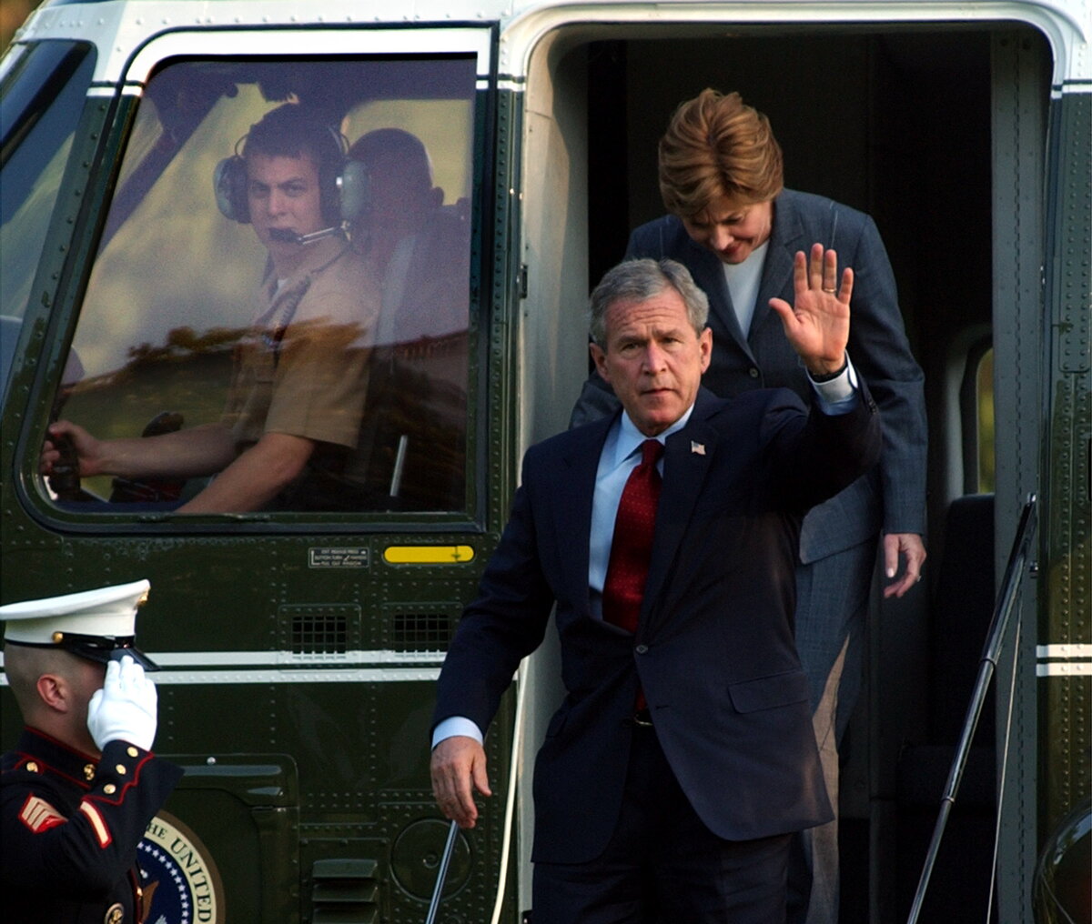 Bradley Harms in the pilot seat of a helicopter as president Bush and first lady Laura Bush exit the helicopter