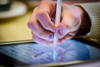 person writes with a stylus on a tablet