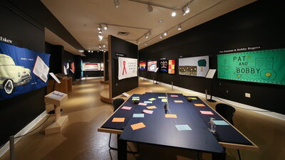 The Spurlock Exhibit Sewn in Memory. AIDS Quilts hang on a wall in a gallery space