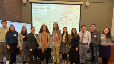 organizing committee and keynote speaker standing in a conference room in front of a screen