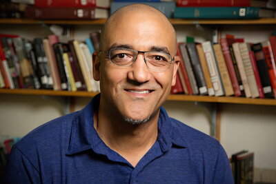 Kevin Mumford headshot with bookshelves behind
