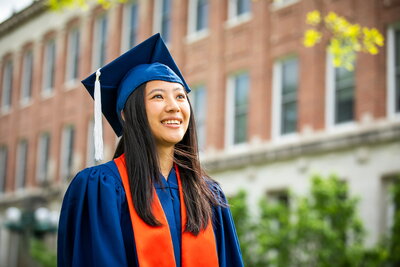 Woman in cap and gown before Lincoln Hall.