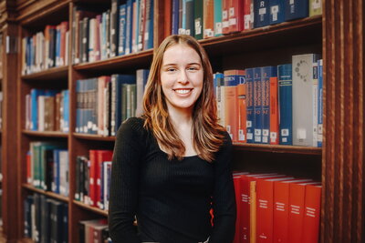 young woman standing before library books