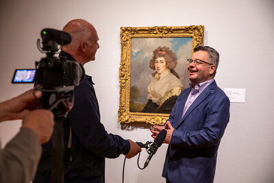 Craig Koslofsky filming an interview in front of a painting.