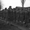 Black WACS stand at attention in two rows in uniform while their commanders walk down the line to inspect them.
