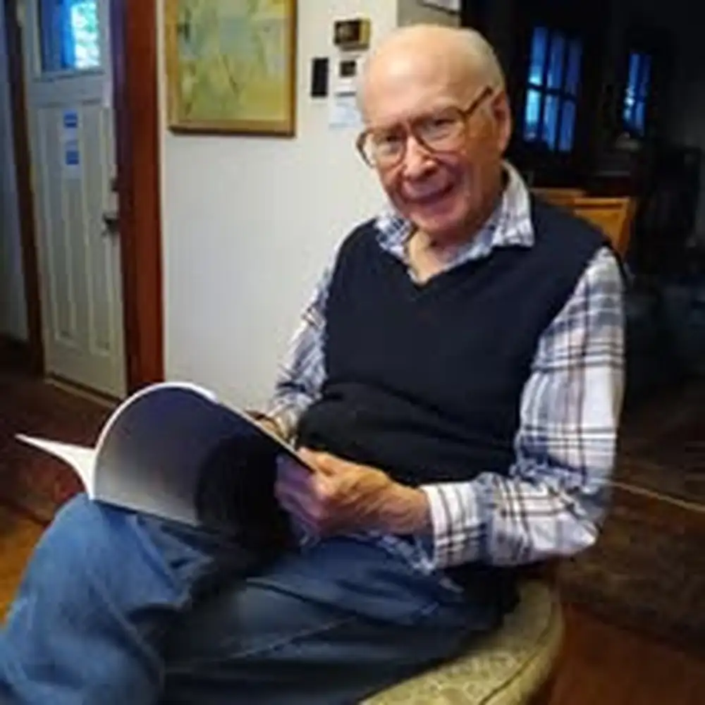 Robert McColley holding an open book in his home