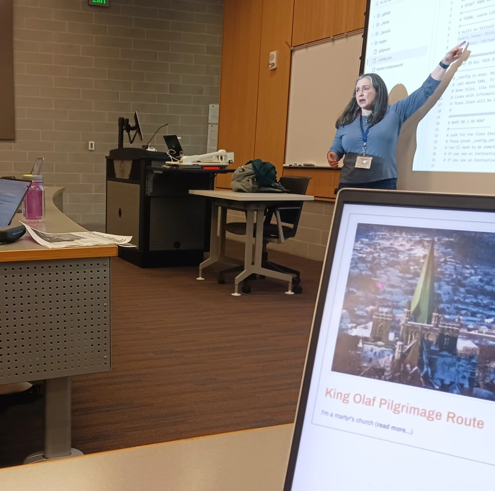 Kalani Craig stands at the front of the room pointing at a screen.