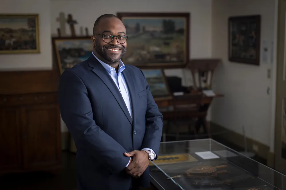 Nile Blunt standing in his office surrounded by paintings.