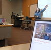 Kalani Craig stands at the front of the room pointing at a screen.