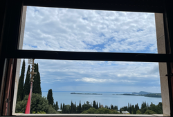 An image of a window looking out at a body of water and a flag.
