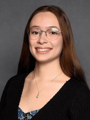 An image of Rachel smiling in front of a plain background.