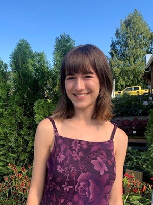 An image of Eva smiling in front of foliage.