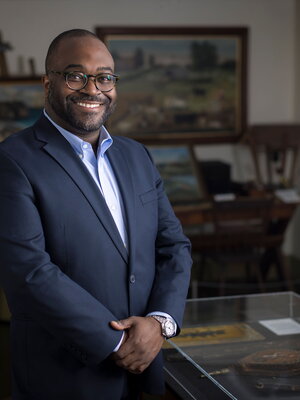 Nile Blunt standing in his office surrounded by paintings.