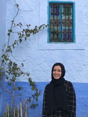 Yasmeen Ragab pictured outside, next to a tree and blue wall 