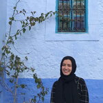 Yasmeen Ragab pictured outside, next to a tree and blue wall 